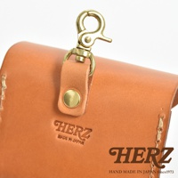 職人手作皮革耳機收納包 KF-4，採用淺棕色皮革材質，配有黃銅色金屬扣環及固定帶，左側印有「HERZ MADE IN JAPAN」字樣，右側有品牌Logo與「HAND MADE IN JAPAN Since1973」字樣。