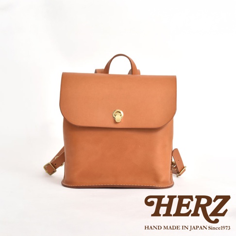 棕褐色皮革翻蓋迷你後背包，配有金色旋轉鎖扣和可調式肩帶。