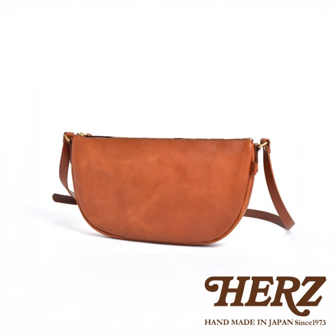 日本HERZ職人手作皮革半圓馬鞍包，近拍皮革材質，展示品牌標誌。