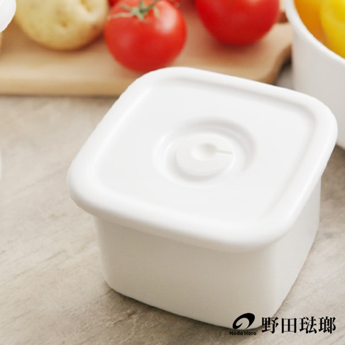 白色方形琺瑯保存容器，帶有圓形閥門的白色密封蓋，置於木質桌面。