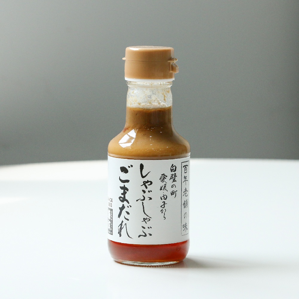 玻璃瓶裝火鍋芝麻沾醬，醬體為淺棕色，瓶蓋為淺褐色，瓶身貼有白色標籤，標籤上有日文文字和紅色裝飾。