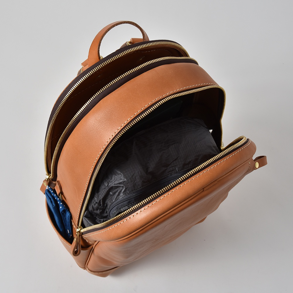 職人手作皮革多功能後背包 R-21，經典棕色，光滑皮革材質，主隔層打開，內有黑色物品。側邊口袋露出藍色點點雨傘。