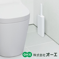 白色超薄浴廁清潔刷，刷柄直立收納於簡潔的白色方形筆筒式刷座內，放置於白色磁磚牆角與地面旁，一旁為部分白色的馬桶。