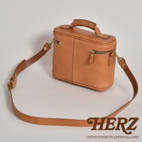職人手作淺棕色皮革軟皮相機包，設有提把及可拆卸肩帶，拉鍊開合，風格簡約。