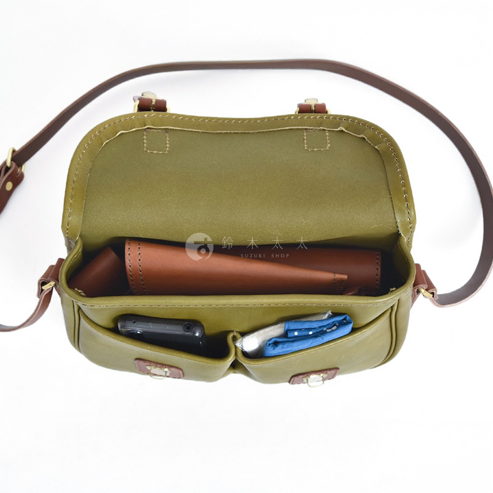 橄欖綠皮革傳統釣魚包，打開內部，可見棕色皮革製品及手機、藍色印花布料。包包配有深棕色皮革肩帶。