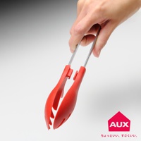 手持一對紅色不沾桌快手料理夾，料理夾由不鏽鋼夾臂和紅色矽膠夾頭組成，夾頭設計有方便夾取的凹槽。