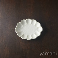 一個18公分的白色六魯粉引花型橢圓料理盤，盤緣有明顯的花瓣狀凹凸紋路，整體呈現質樸的手工質感，置於深棕色木紋背景上。