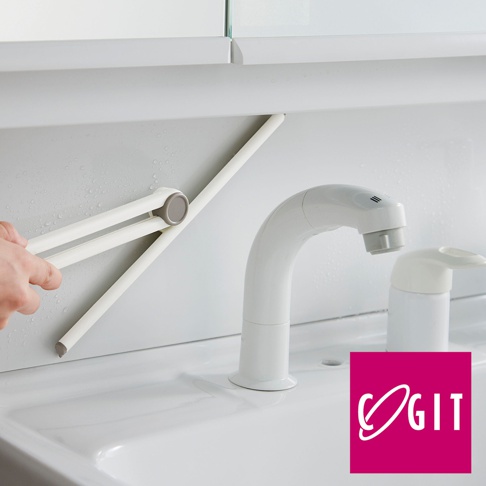 白色可摺疊刮水刷，帶有灰色連接點，置於水槽旁，旁邊有一個白色水龍頭和一個白色皂液器。