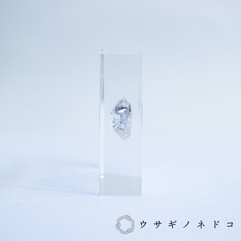透明方形壓克力塊中封存著一顆帶有清晰切面的天然水晶。