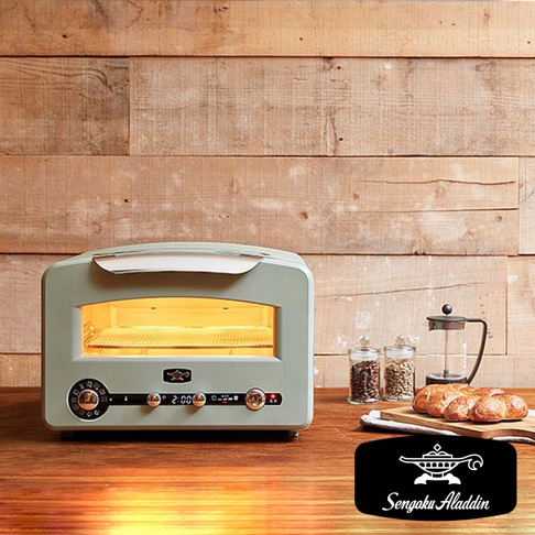 淺綠色復古多用途烤箱，設有玻璃門和銀色把手，內部烤架亮著黃光。烤箱前方有銀色旋鈕、數位顯示螢幕和按鈕。背景為木紋牆壁。