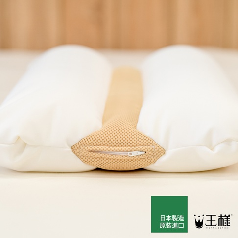 模式B： 一張白色枕頭的特寫，中央有咖啡色的網狀透氣材質，枕頭側面有拉鍊，下方有王樣品牌標誌和日文文字。