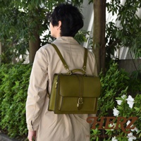 橄欖綠皮革製成的職人手作三用單扣商務後背包，附有可調節肩帶，背包正面有裝飾性皮帶和金色搭扣，適合商務場合。