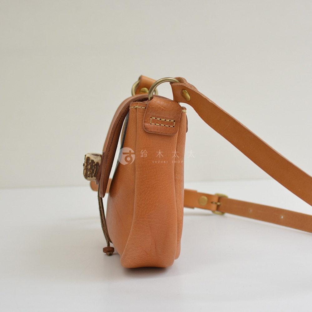 棕色皮革肩背包，帶有鹿角扣和可調節的皮革肩帶，包身側面有縫線細節。