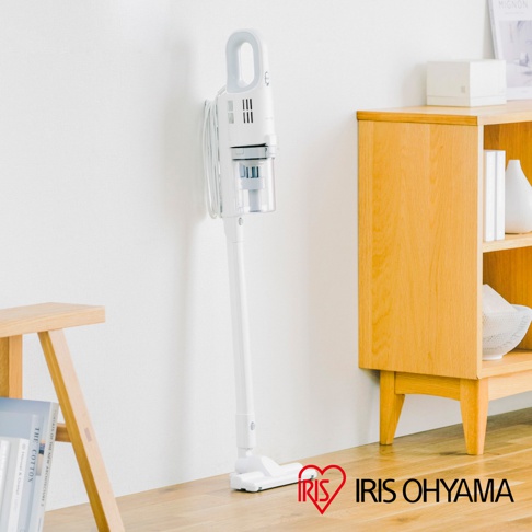 白色手持式吸塵器，帶有透明集塵筒和銀色細節，靠牆直立，下方可見白色地板吸頭。