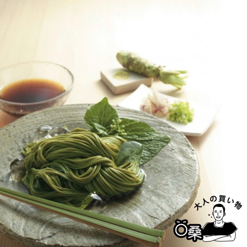 綠色海苔蕎麥麵盛裝於灰色盤中，旁有冰塊、綠葉裝飾，以及一小碟醬汁、磨碎的山葵、蔥花和蒜片。