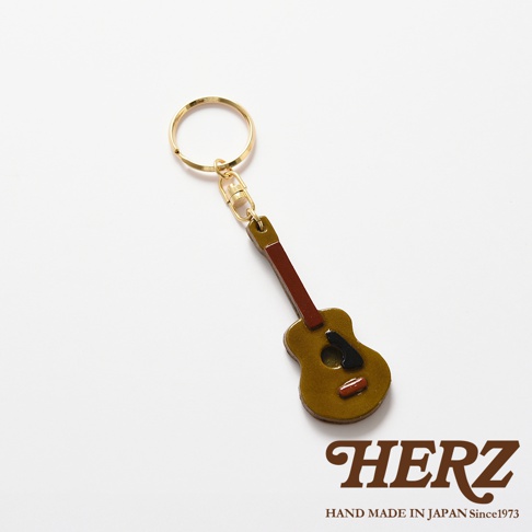 職人手作皮革吉他造型鑰匙圈，黃褐色吉他主體，搭配棕色琴頸，黑色音孔裝飾，金色金屬鑰匙圈。