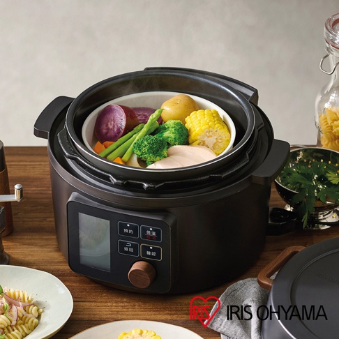 黑色電子壓力鍋，內有蒸籠，盛有雞胸肉、馬鈴薯、紫薯、玉米、蘆筍、花椰菜與紅蘿蔔等食材。鍋身設有觸控螢幕與旋鈕。