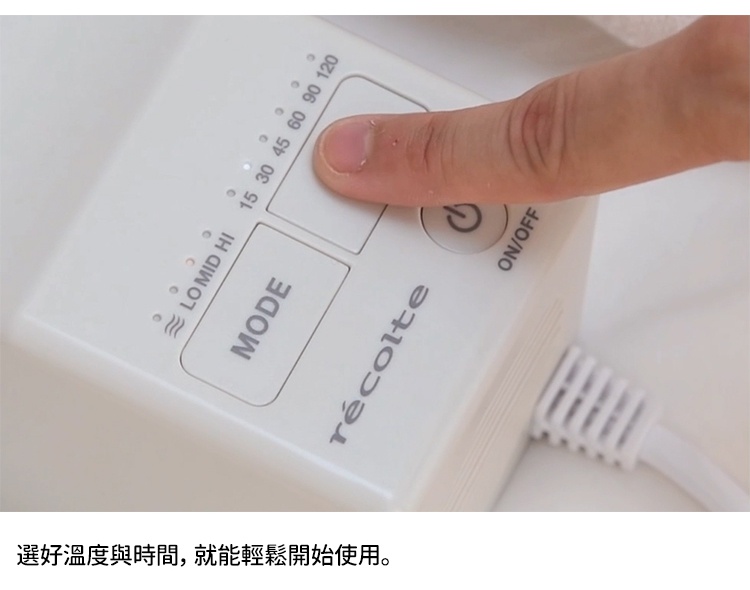 用手指觸碰 recolte 烘被機的電源按鈕，旁邊顯示著模式和時間選擇。