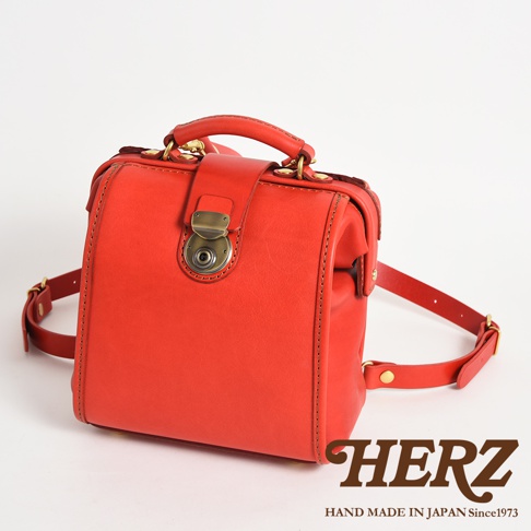 職人手作皮革迷你後背醫生包，鮮紅色，方形包身，頂部有提把，前方有金屬鎖扣，配有可調節的皮革後背帶。