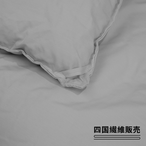 淺灰色雙人被子一角，材質為布料，有縫線和固定用的織帶。