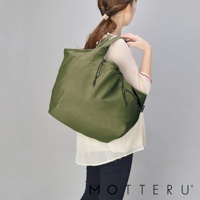 一位女性身背一個橄欖綠的大容量束口摺疊環保隨行袋，袋子為尼龍材質，兩側有束帶設計，可側肩背。