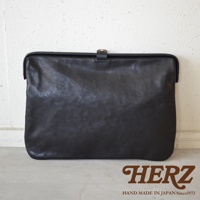 職人手作黑色皮革Organ手拿包，簡約設計，帶有金色金屬扣環，展現天然皮革的紋理質感。