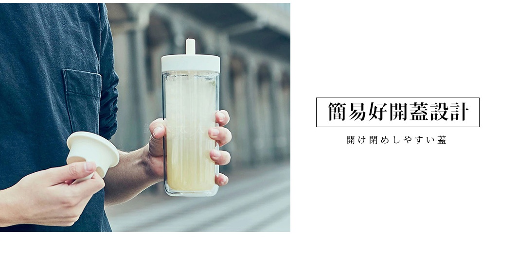 手持TO GO BOTTLE雙層隨手瓶，瓶身為透明玻璃材質，內含淺黃色液體，瓶蓋和吸管為白色。