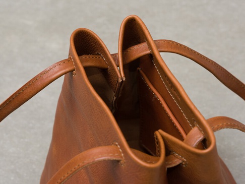 棕色皮革抽繩肩背手提托特包，細節展現精緻縫線與柔軟皮革質感。