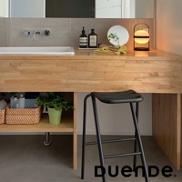 黑色金屬吧檯椅，椅面為黑色塑膠材質，椅腿設計簡約，搭配木紋檯面。