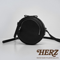 黑色皮革製成的小圓包，包身圓潤，正面設有拉鍊隔層，搭配銀色拉鍊和皮革拉頭。