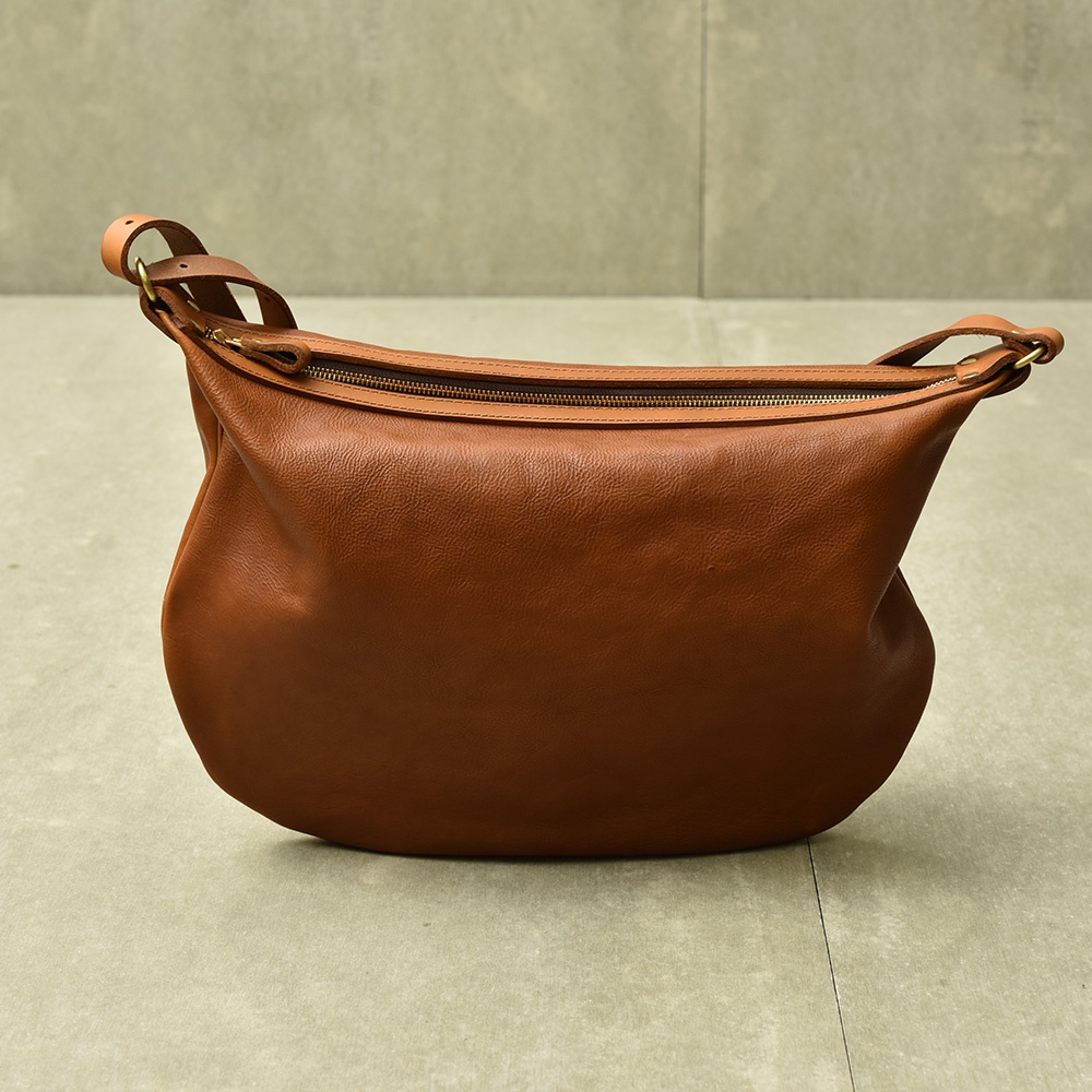 職人手作皮革Organ單肩半月包，採用棕褐色皮革製成，包身呈現柔軟的半月形狀，配有拉鍊開口和皮革肩帶。