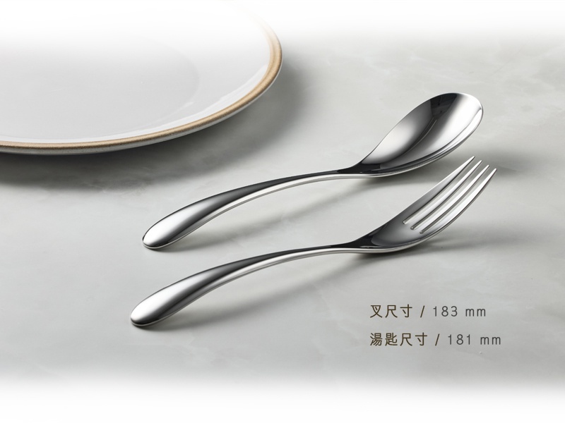 叉子尺寸183毫米，湯匙尺寸181毫米，兩個都是不鏽鋼材質，光滑亮麗，放在淺色背景上，背景右側有一個部分被遮擋的白色盤子。