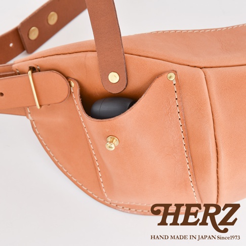 HERZ 職人手作皮革大容量斜背包 F-1，近拍特寫，展示皮質細節、金屬扣環、縫線工藝，以及包包側邊的置物小袋。
