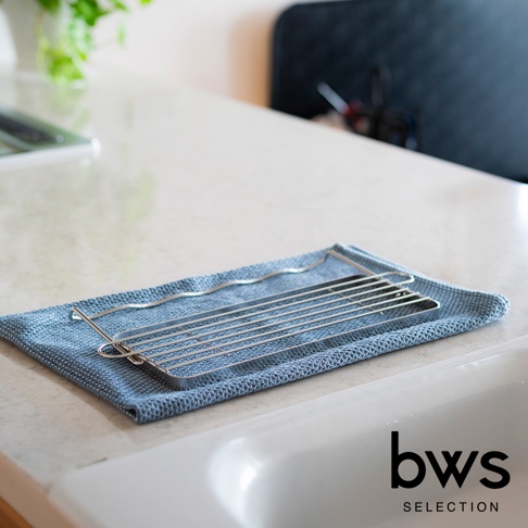 銀色不鏽鋼折疊杯壺瀝水架，置於藍色紋理布上，靠近白色水槽。