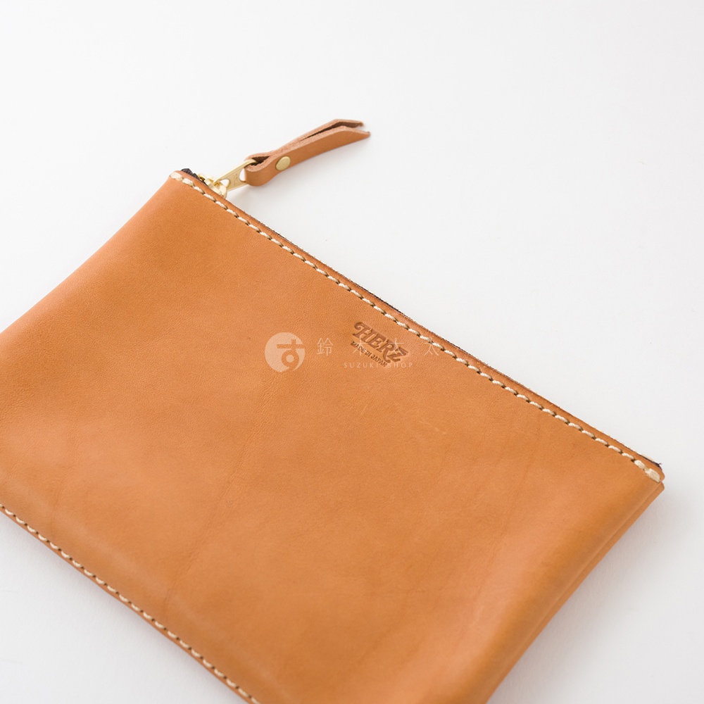 駝色皮革長方形拉鍊收納包，帶有金色拉鍊頭和同色皮革拉環，邊緣縫線清晰。包體表面壓印品牌標誌。