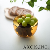 琥珀色玻璃點心碗盛有綠色和紫色葡萄，碗身圓潤，復古設計，碗後方有切片麵包和綠葉裝飾。