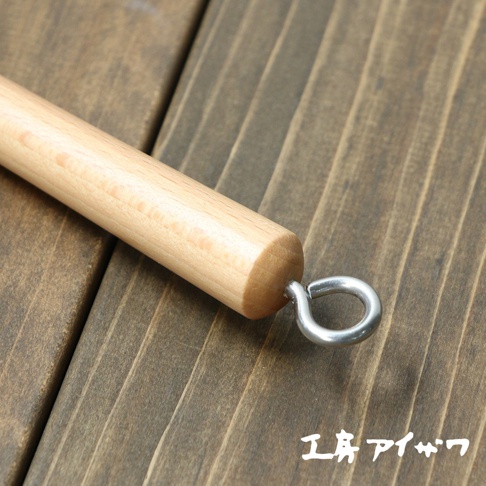 VEGET 不鏽鋼木柄削皮刀，特寫木質手柄末端，連接金屬掛環，背景為深色木紋桌面。