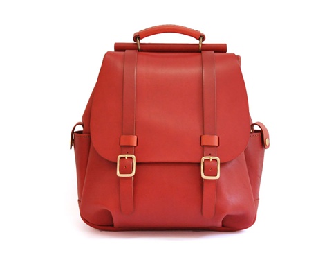 紅色皮革雙扣後背包，配有頂部提把、可調節肩帶和金色金屬扣環。