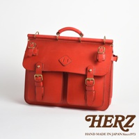 職人手作皮革旅行包 A-102，紅色，採用真皮材質，設有翻蓋、雙口袋、多個皮帶扣和頂部提把。