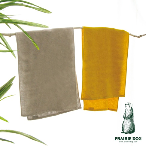 兩條 Prairie Dog ARLO 系列今治有機棉速乾半浴巾懸掛在木枝上，左側為灰色，右側為芥末黃色，旁有綠色植物葉片點綴，右下角印有 Prairie Dog 品牌名稱與圖像。