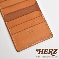 日本HERZ皮革二折式卡片鈔票夾，呈現職人手作的精緻細節，以棕褐色皮革製作，內有多個卡片夾層，印有HERZ MADE IN JAPAN字樣，底部還有HERZ HAND MADE IN JAPAN Since1973的品牌標誌。