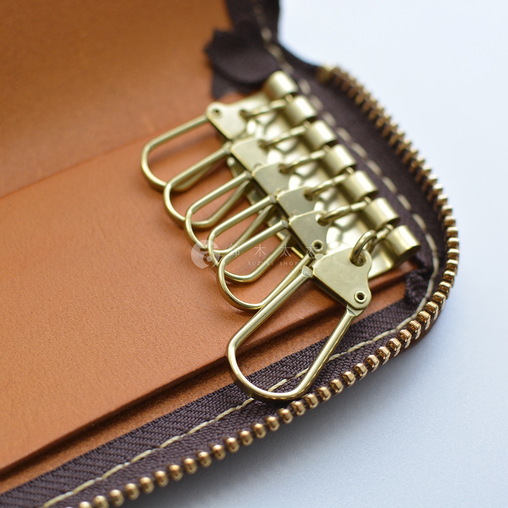 職人手作皮革鑰匙包，內部設有六個黃銅色鑰匙鉤，並有拉鍊開合。