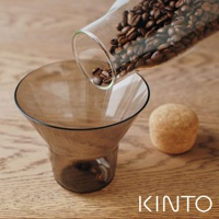 棕色玻璃濾杯，上方有一個玻璃分享壺，其中裝有咖啡豆，正在傾倒。右側有一個軟木塞。