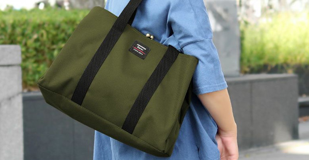 一個綠色的托特包，帶有黑色織帶和一個品牌標籤。