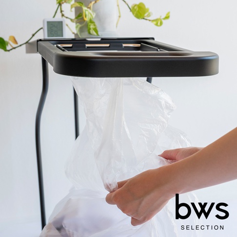 bws SELECTION 品牌標誌旁，一隻手正將透明垃圾袋套入黑色的簡約滑蓋式垃圾架。