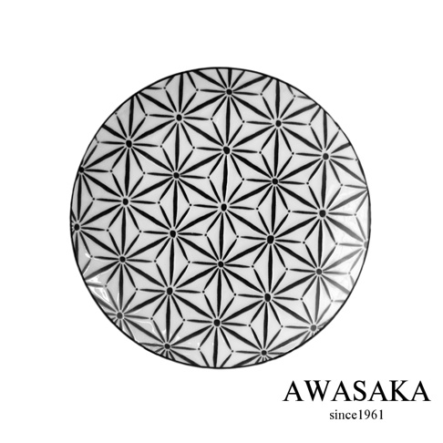 一個白底圓盤，上面佈滿黑色的幾何圖案，類似星形或花瓣的重複排列，營造出日式和風的視覺效果。盤子邊緣光滑，材質應為陶瓷。