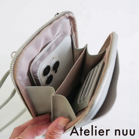 Atelier nuu 的淺灰色皮革隨身手機包，呈現開口視角，內部展示了放置手機的夾層以及側邊的卡片收納槽，整體設計簡約優雅，方便日常隨身攜帶使用。
