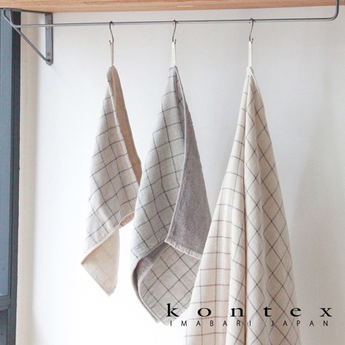 三條草木染格紋有機棉浴巾，分別為米白色、淺灰及格紋混色，皆以細緻的格紋圖案呈現。