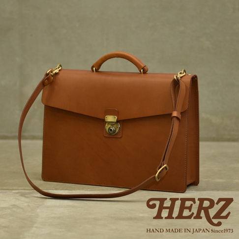 職人手作皮革Organ兩用商務公事包，採用棕色牛皮製成，具備頂部提把、可拆卸肩帶、黃銅色金屬鎖扣及配件，風格經典。