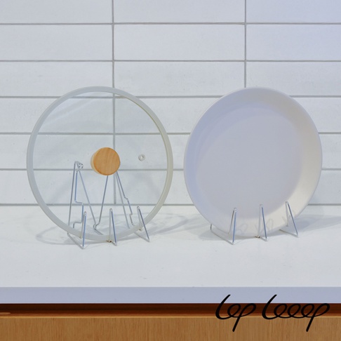 兩個銀色金屬架，左邊架著一個透明玻璃鍋蓋，鍋蓋上有一個木製把手；右邊架著一個白色圓盤。